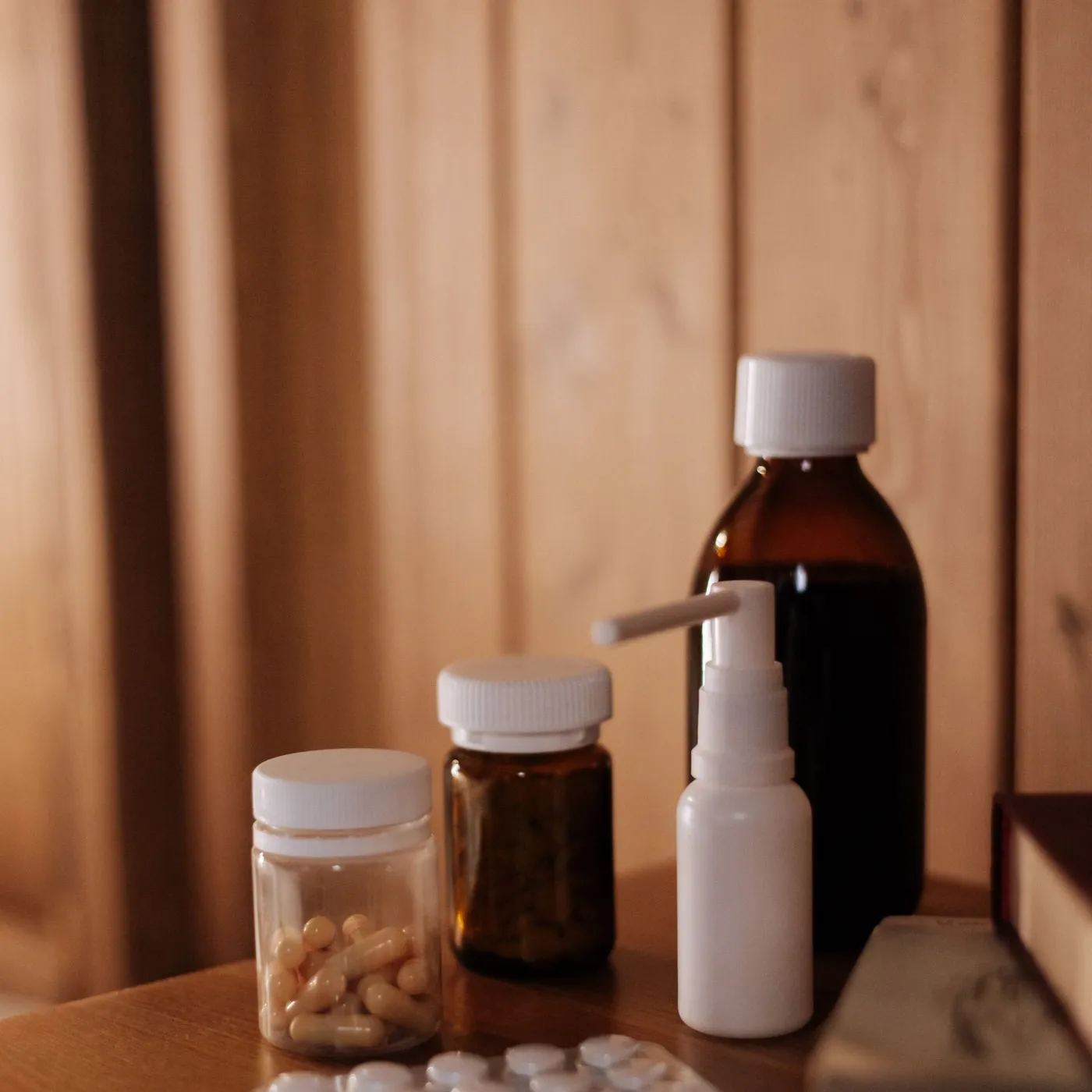 Medicine bottles, a spray and a blister pack on a bedside table